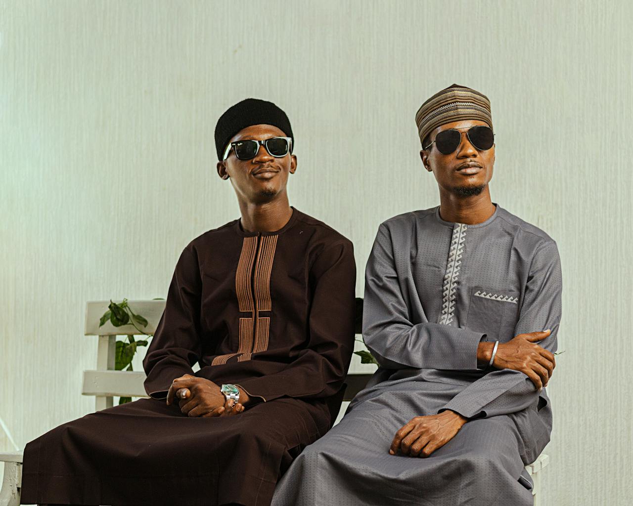 services-01 Two men in traditional Nigerian attire, sunglasses, sit in a modern setting showcasing cultural elegance.