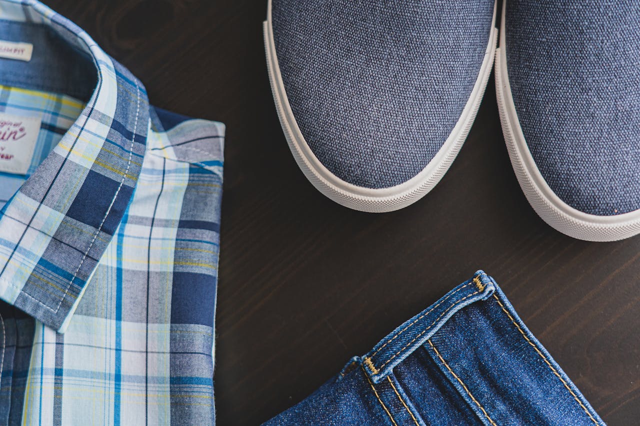 journey Flat lay of a casual men's outfit with checkered shirt, denim jeans, and blue sneakers.